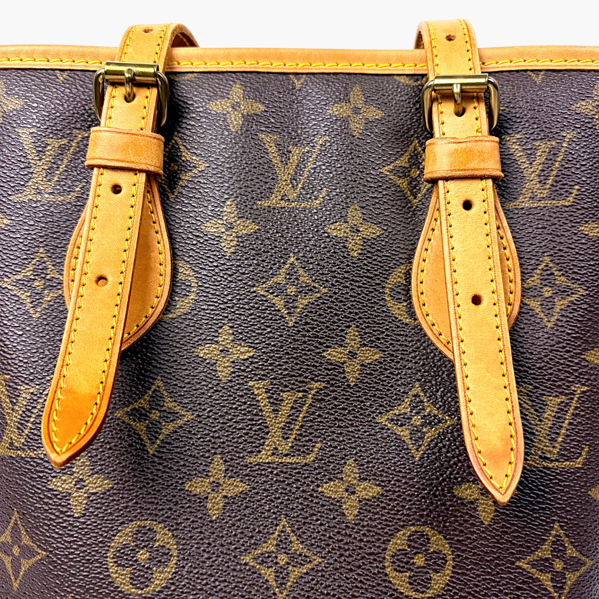 Monogram canvas bucket bag with tan leather strap accents and gold hardware