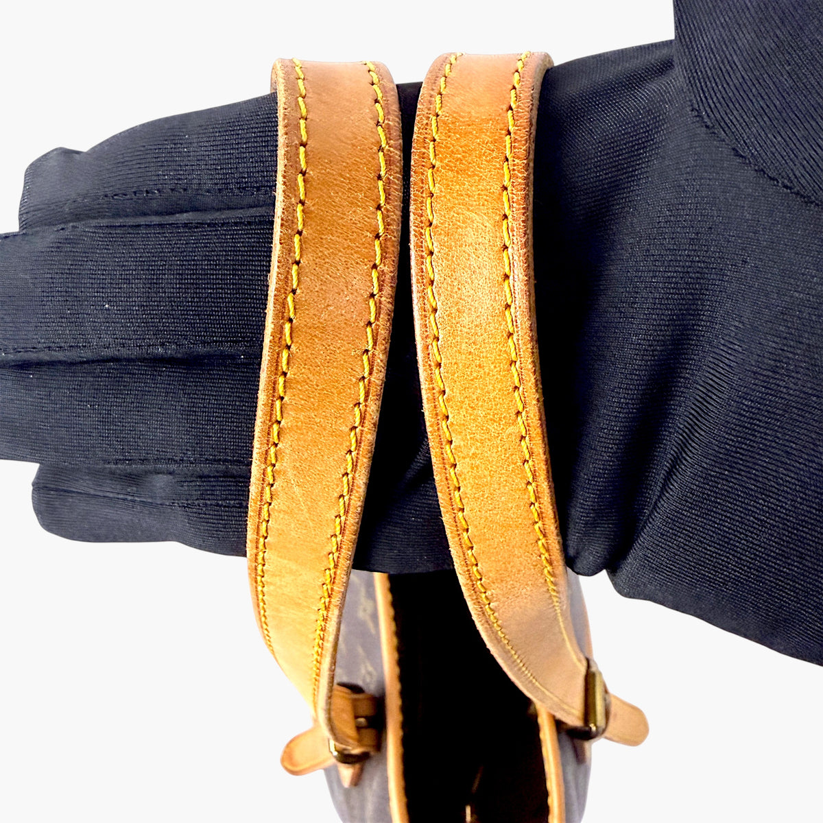 Tan leather handle straps on a monogram canvas bucket bag
