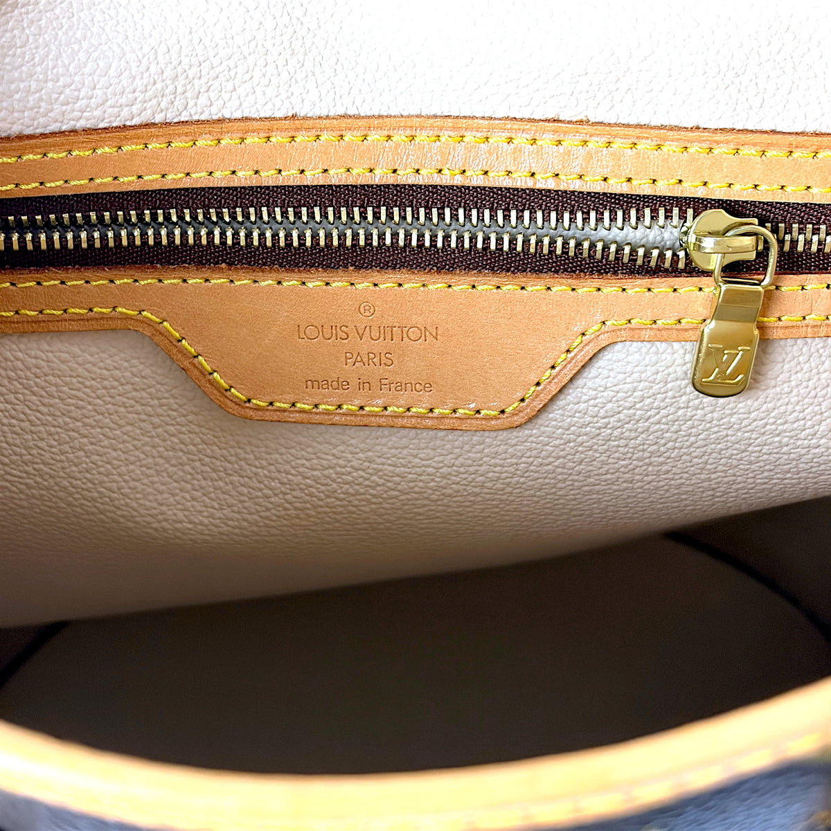 Leather interior tag and gold zipper pull on a monogram bucket bag