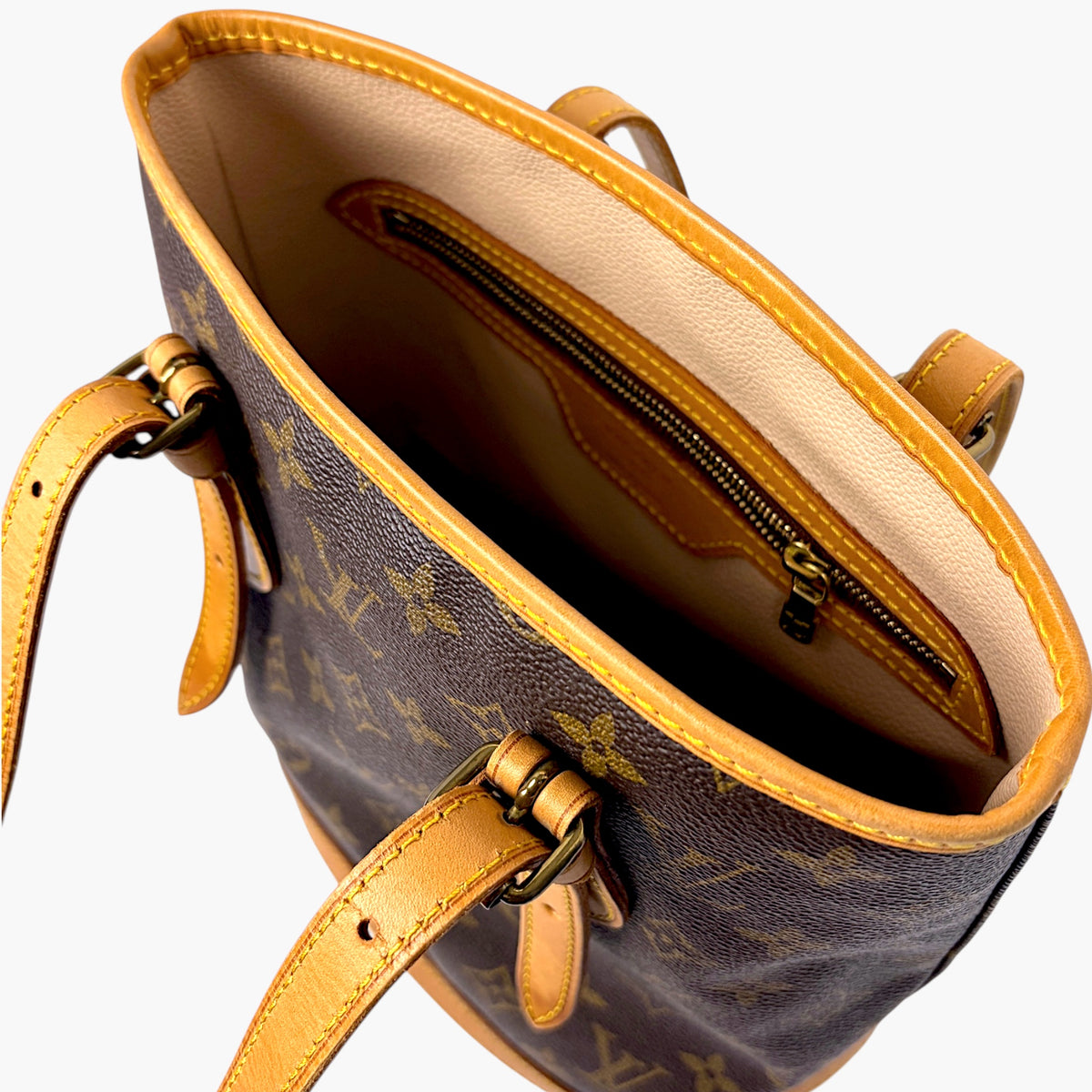 Monogram bucket bag open top with tan leather trim and dual zipper compartments