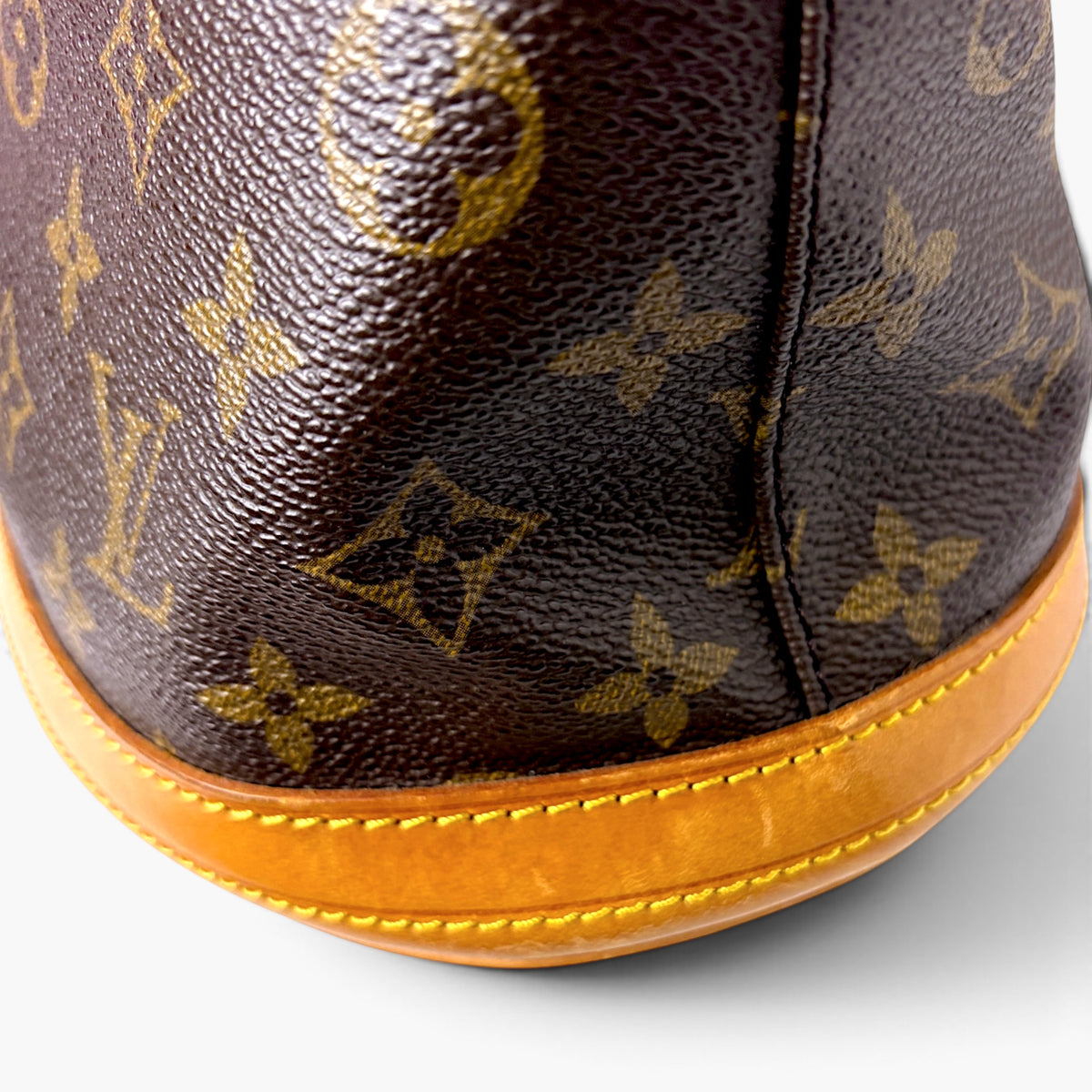 Monogram bucket bag corner with tan piping and textured brown leather exterior