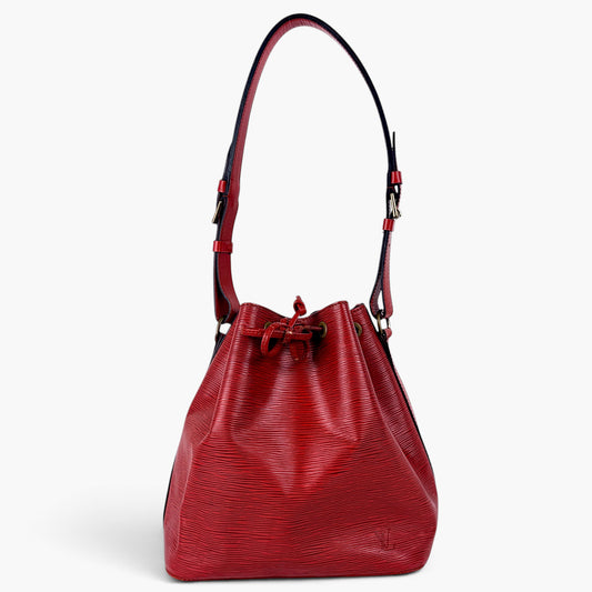 A red textured leather bucket bag with a drawstring closure and a single shoulder strap, photographed against a clean white background.