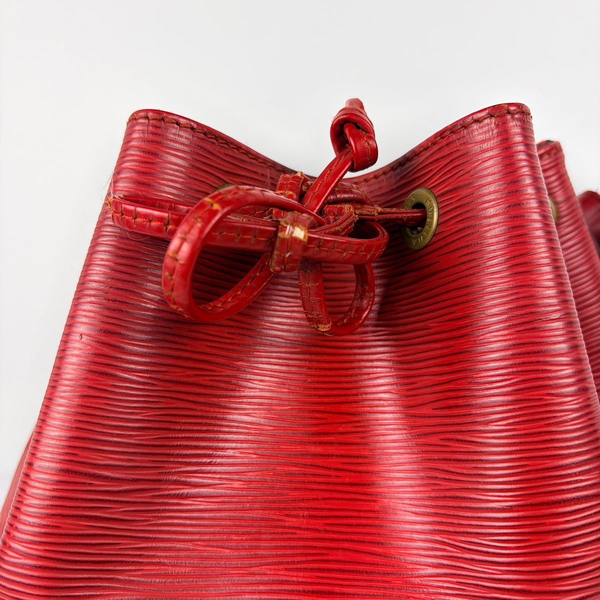 Red leather bucket bag with rolled handles, drawstring closure, and gold-tone hardware