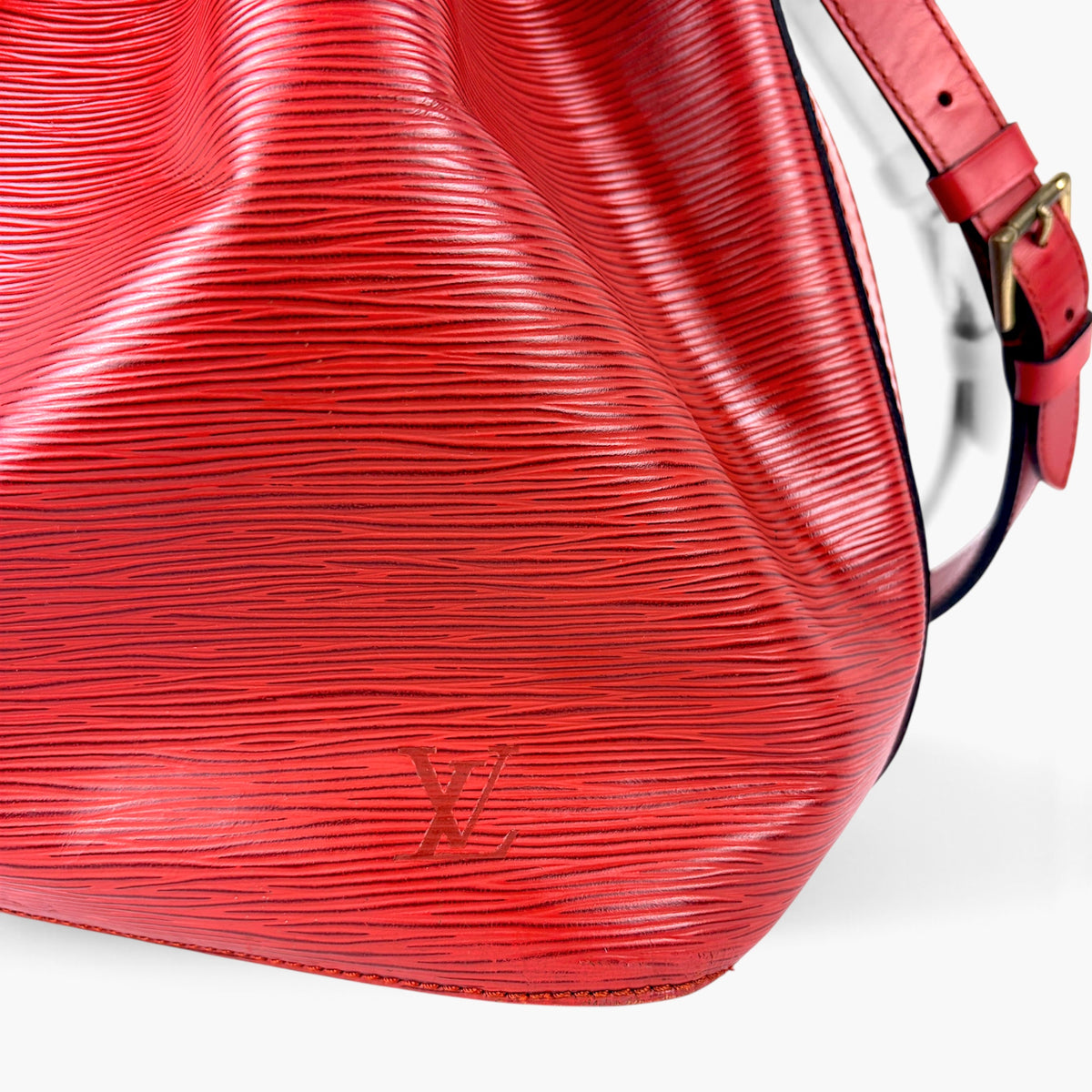 Red textured leather bucket bag side view with gold-tone logo detail