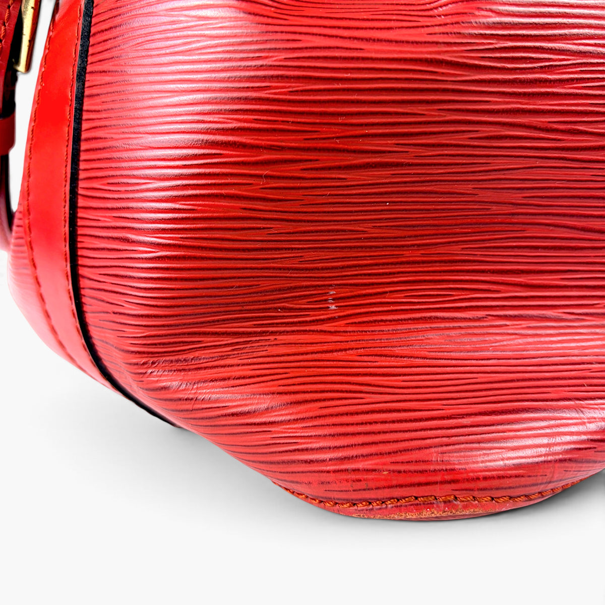 Red textured leather bag with close-up of horizontal wavy grain and edge trim