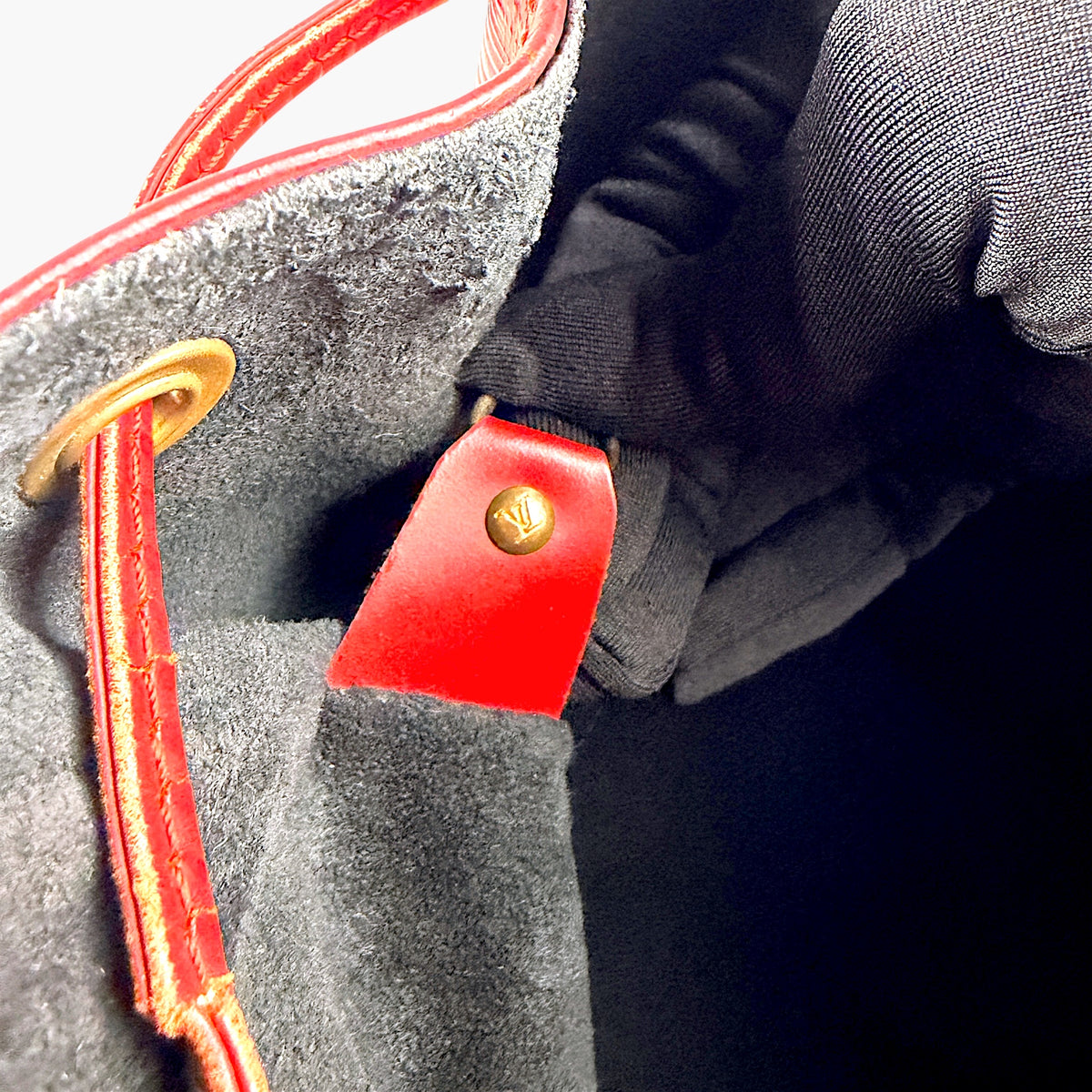 Open bag interior with dark lining and red leather trim around top edge