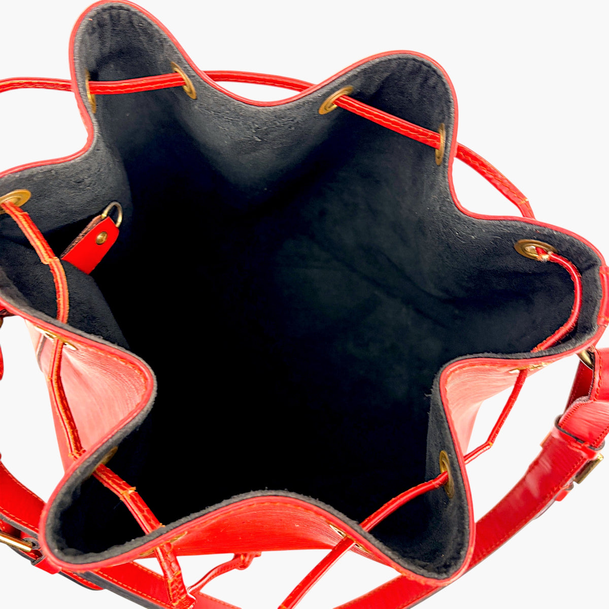 Bucket bag interior view with dark fabric lining and red leather handles and seams