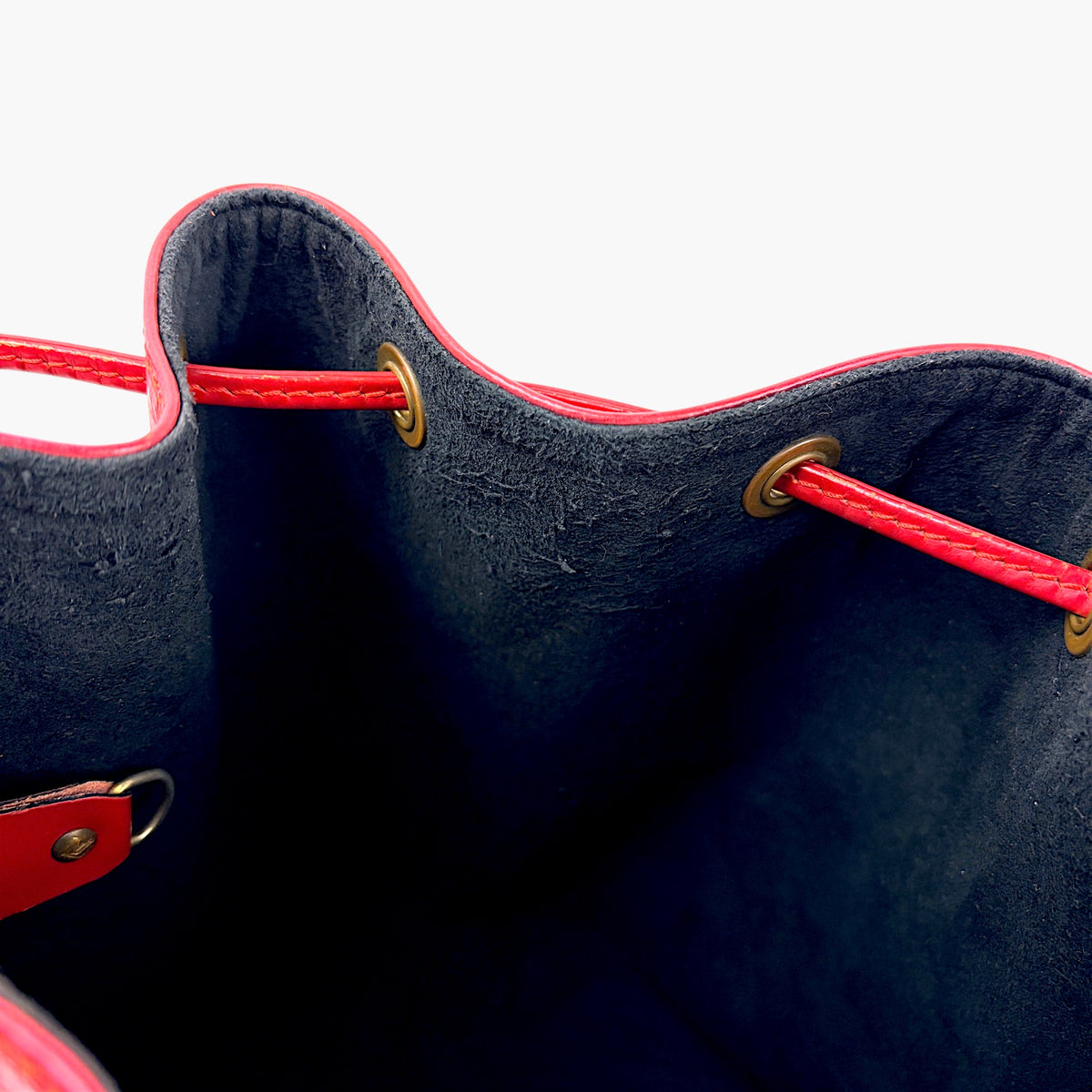 Red bucket bag with navy interior, drawstring top and gold eyelets