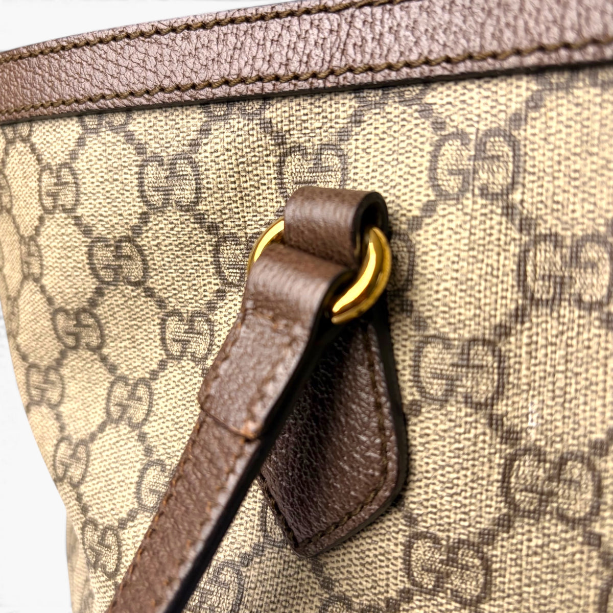 Beige GG monogram tote close-up of dark leather clasp strap with gold ring