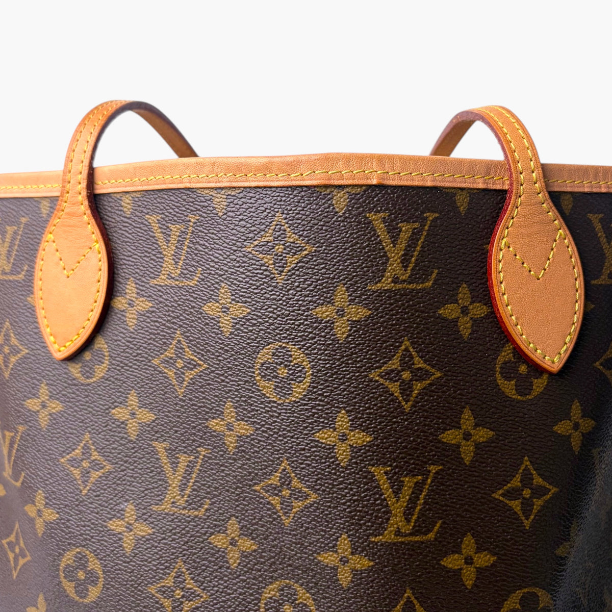 Monogram tote bag front with tan leather corner tabs and curved top handles