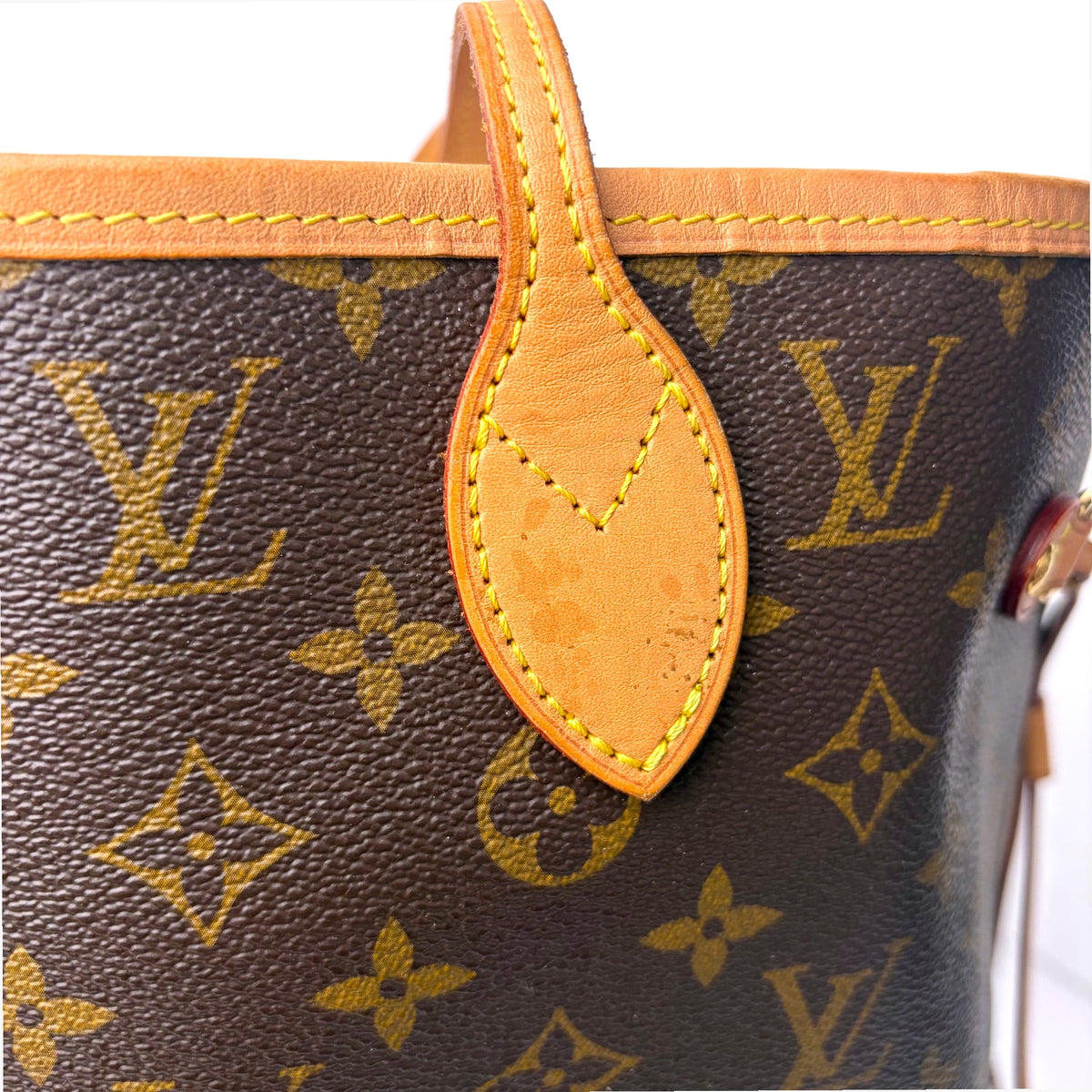Monogram tote bag close-up with tan leather teardrop pull and stitched loop
