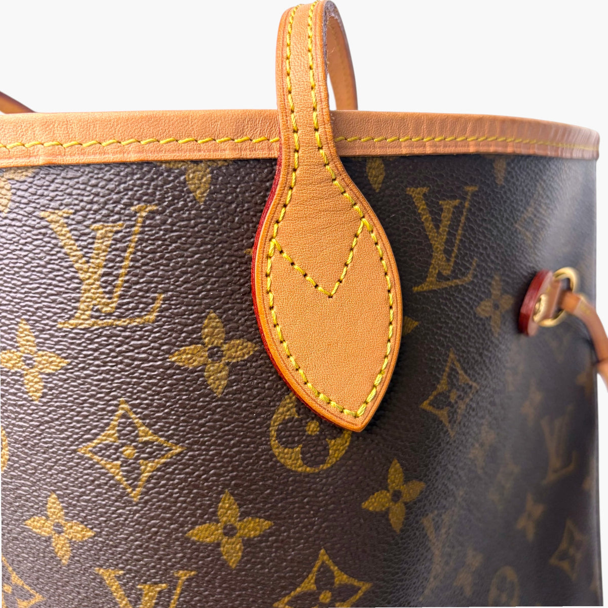 Brown monogram tote bag with tan leather strap, side seam, and metal detail