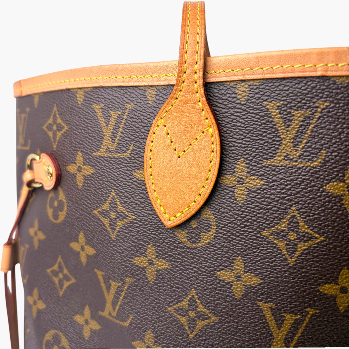 Brown monogram tote bag corner with tan leather strap and small hanging tag