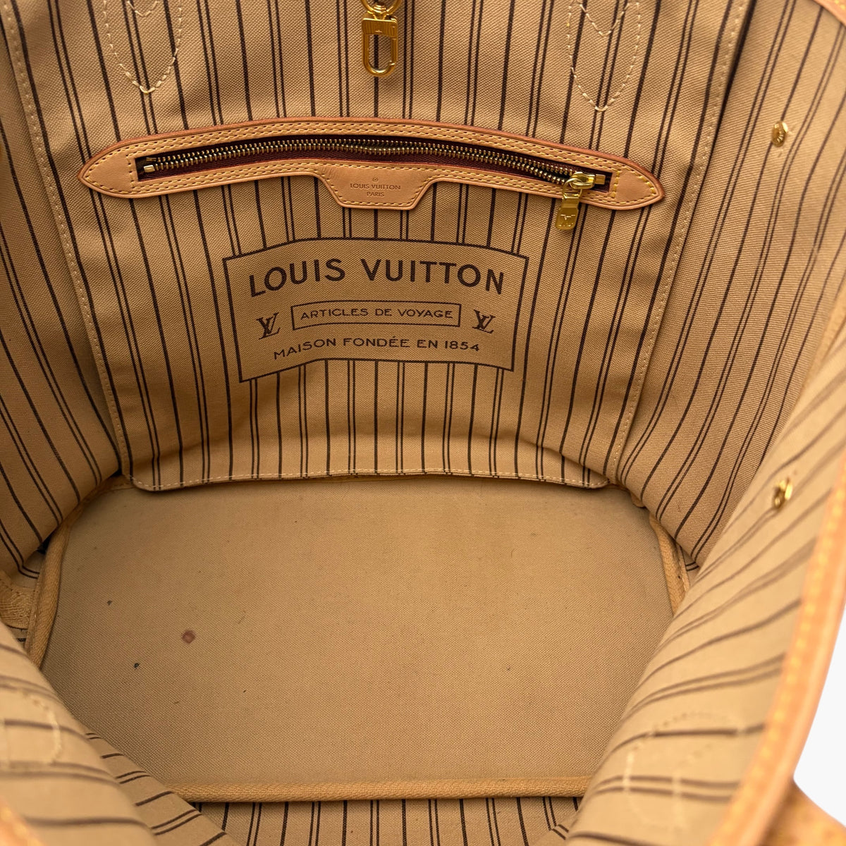 Brown monogram tote interior with striped lining and leather trim at open top