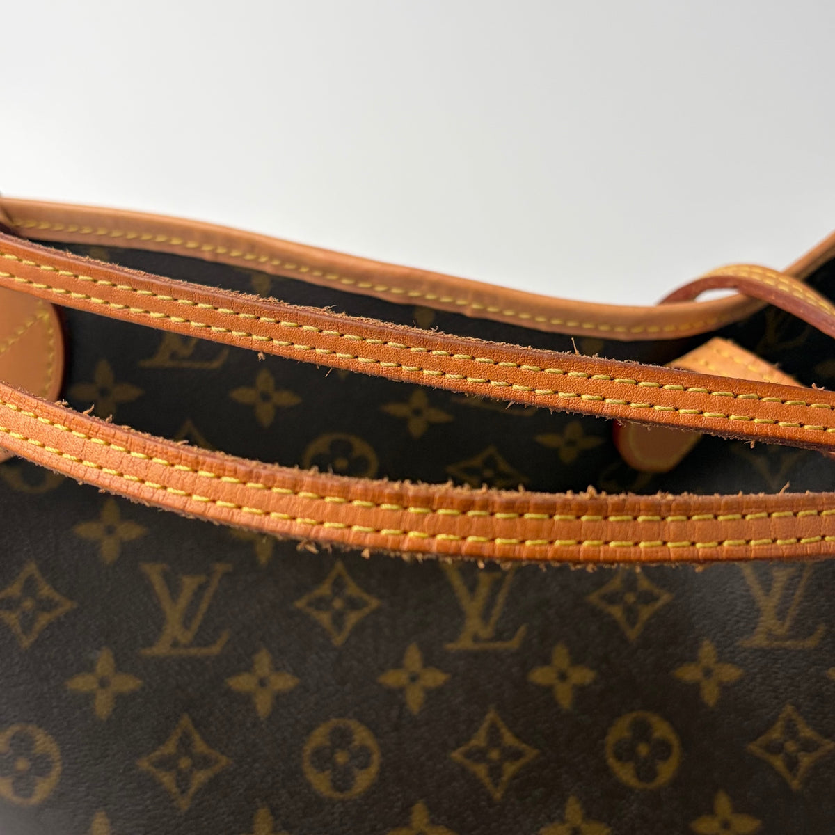 Brown monogram bag with tan stitched edging and leather strap attachment loops