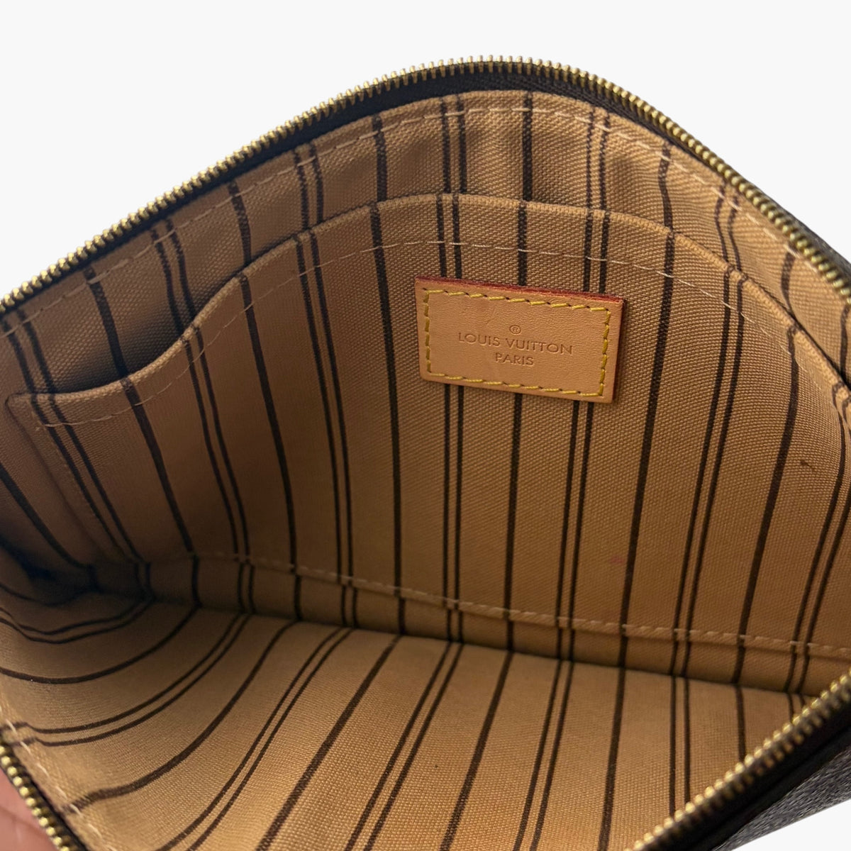 Tote interior with beige striped lining and Louis Vuitton label patch near zipper