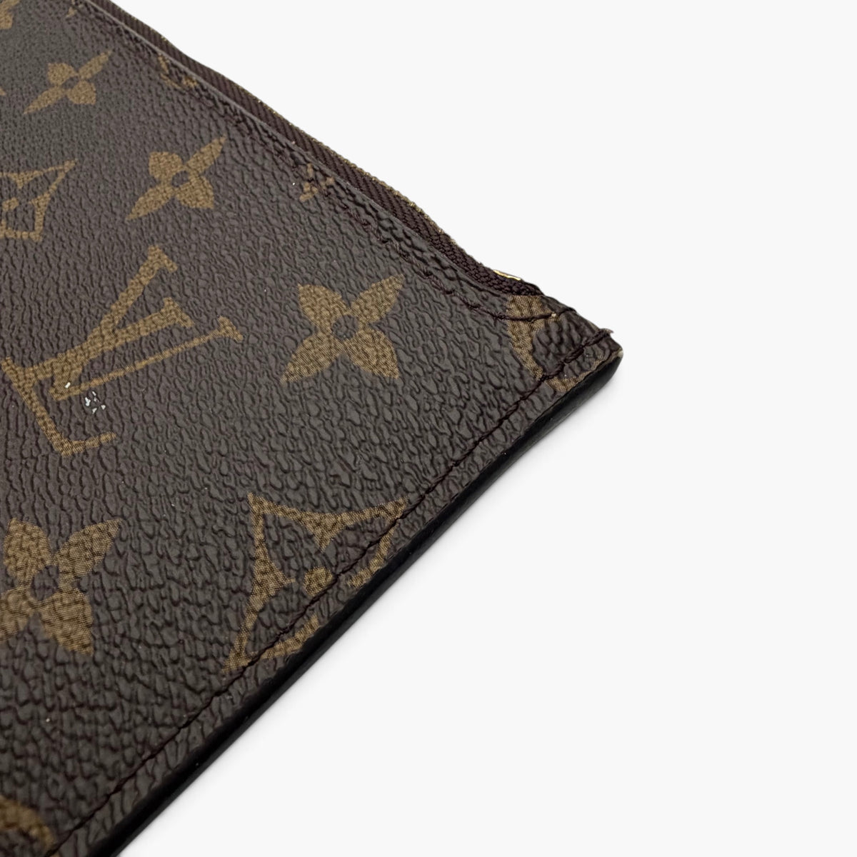 Monogram canvas triangle corner detail with gold motifs and textured finish