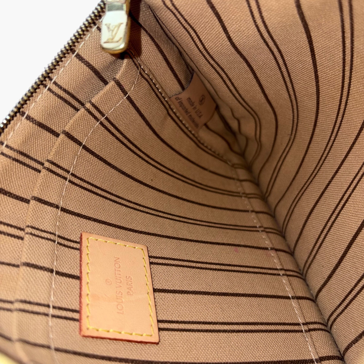 Inside lining view with Louis Vuitton logo patch and zipper area stitching