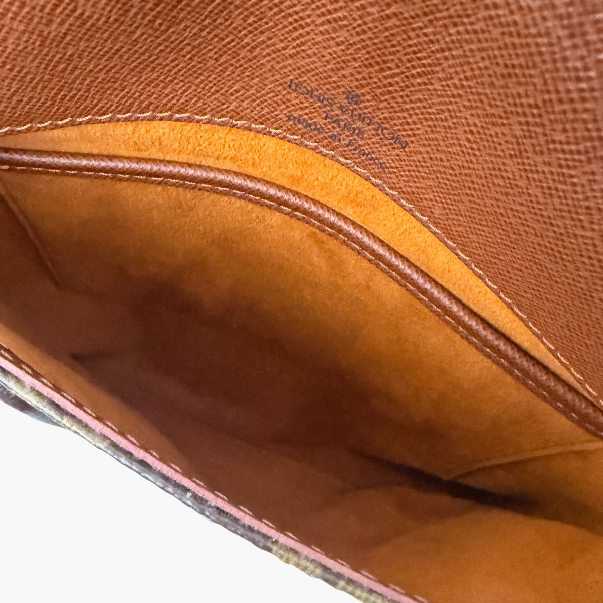 Crossbody bag interior view, tan lining with stitched edge and curved opening