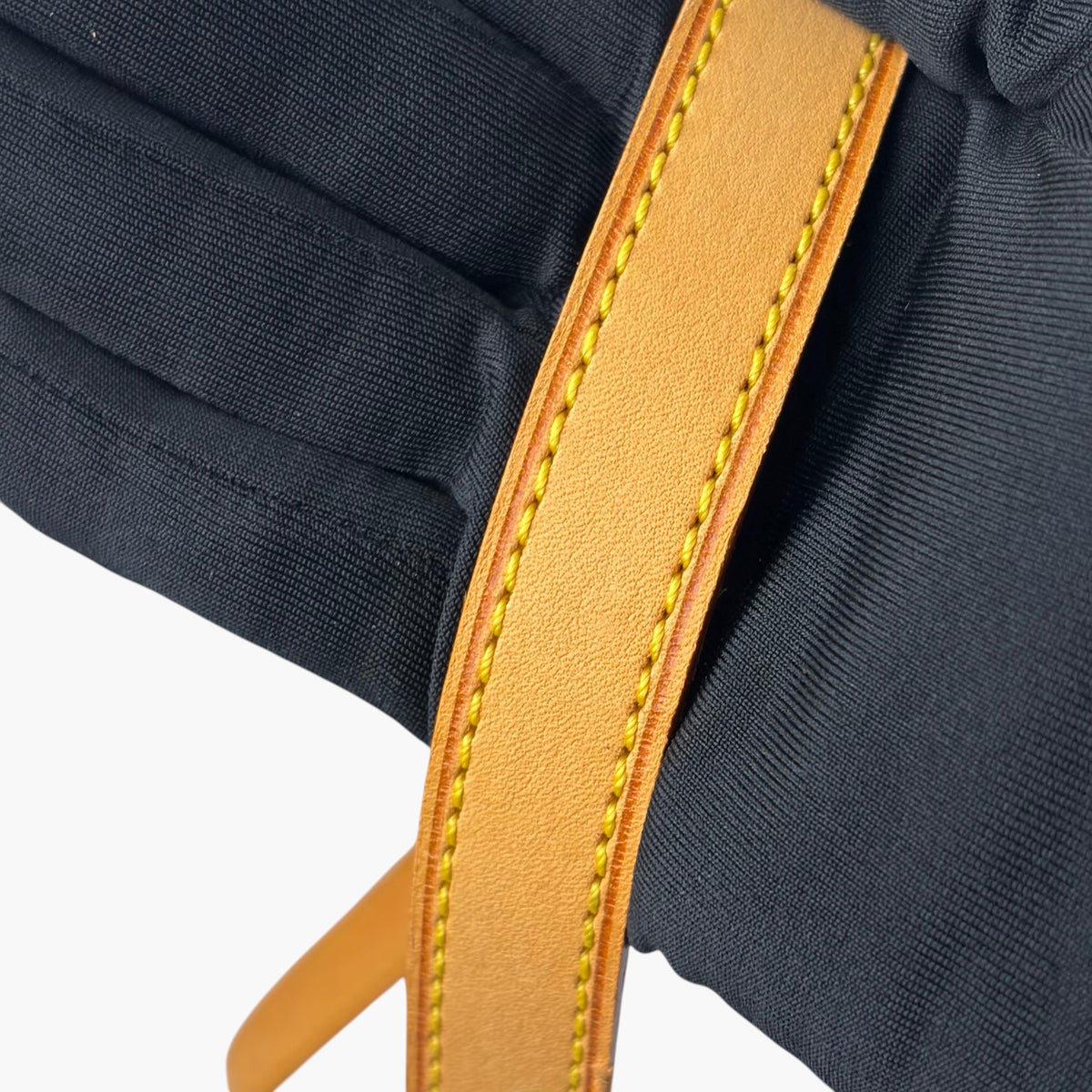 Crossbody bag strap seam detail, tan edging and yellow stitching on dark fabric lining