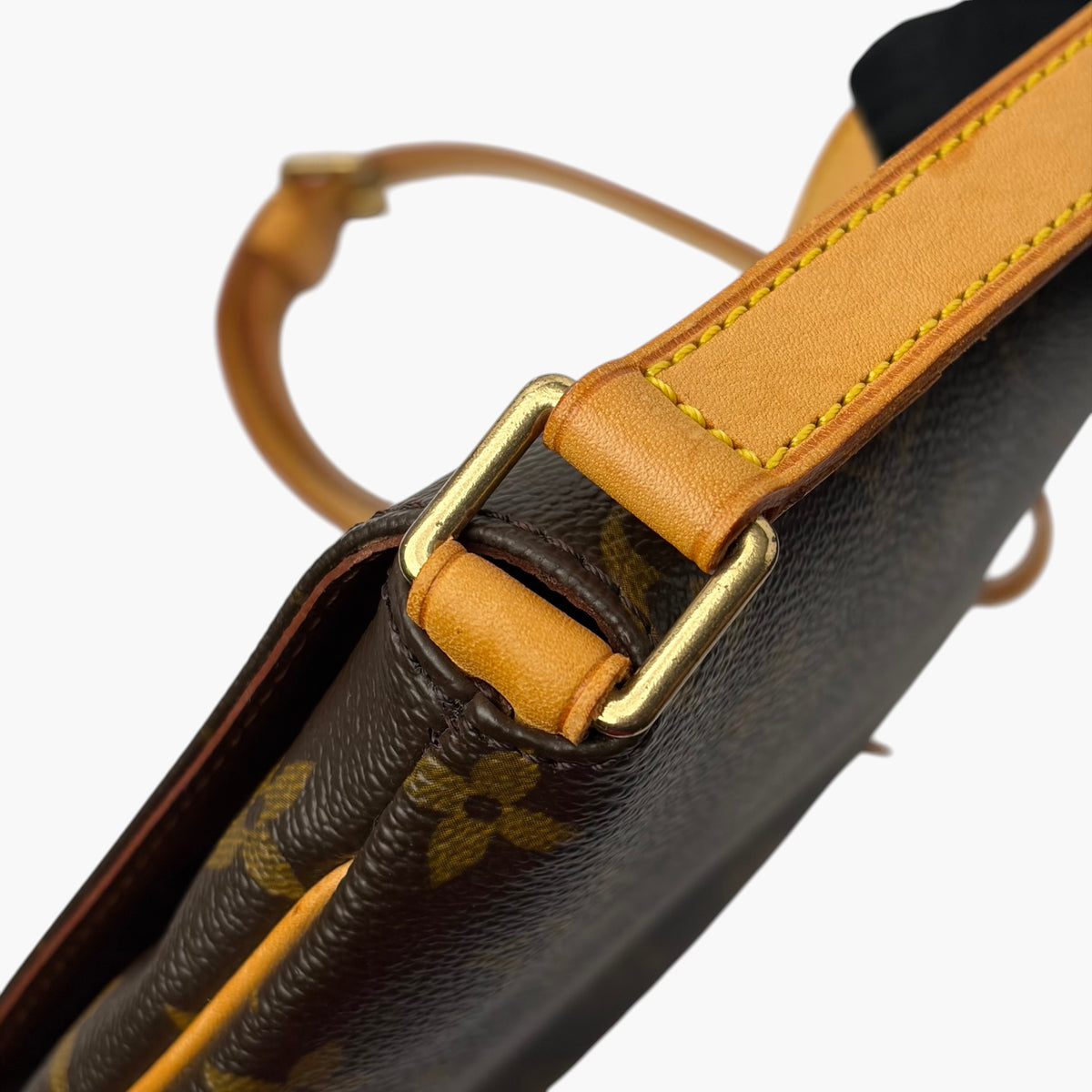 Brown monogram bag with tan leather strap, brass buckle, and pull loop