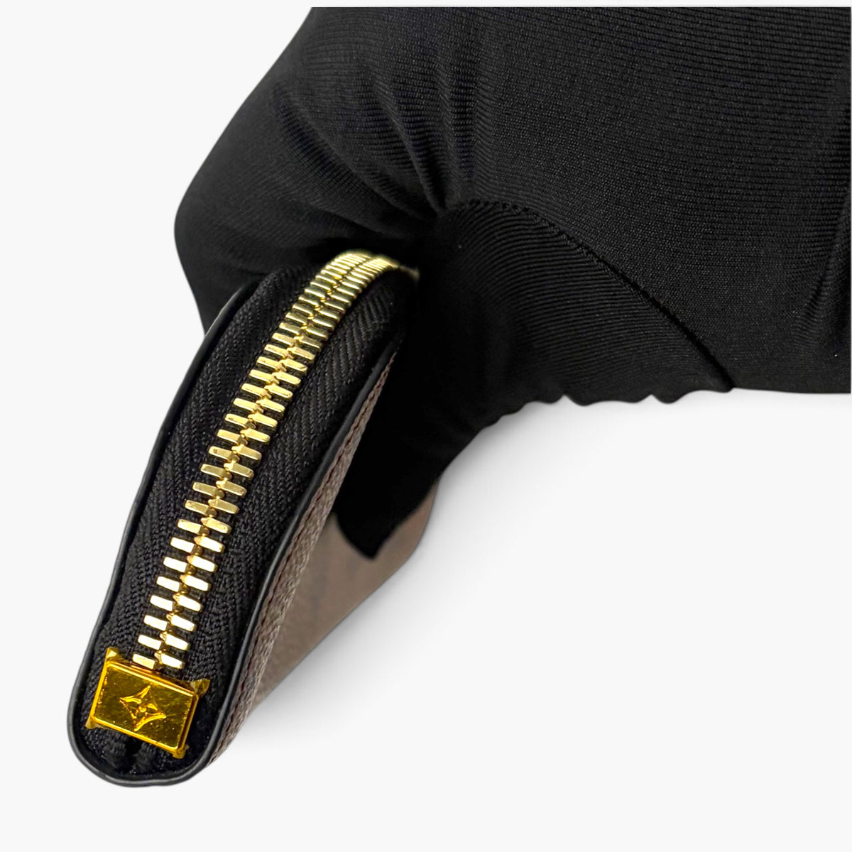 Black pencil case with gold-tone zipper and small square logo tag at zipper end