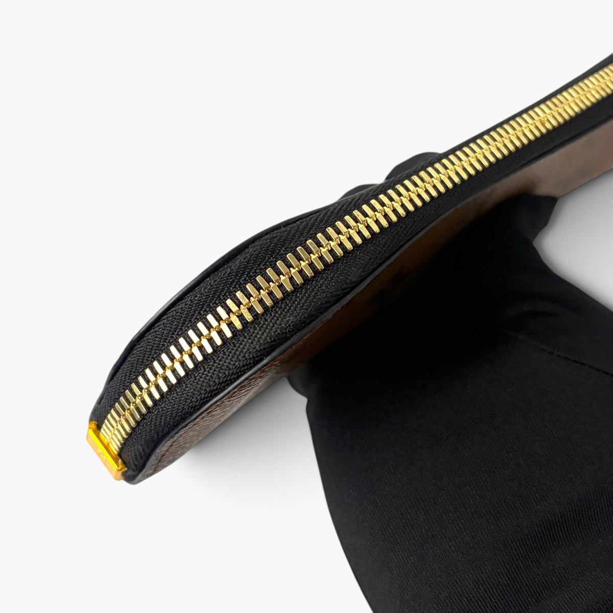 Black pencil case with textured finish and gold zipper, side profile