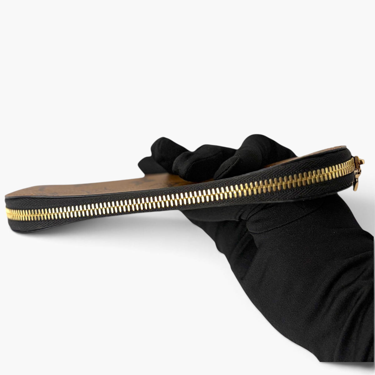 Black pencil case with gold zipper, held open by gloved hand