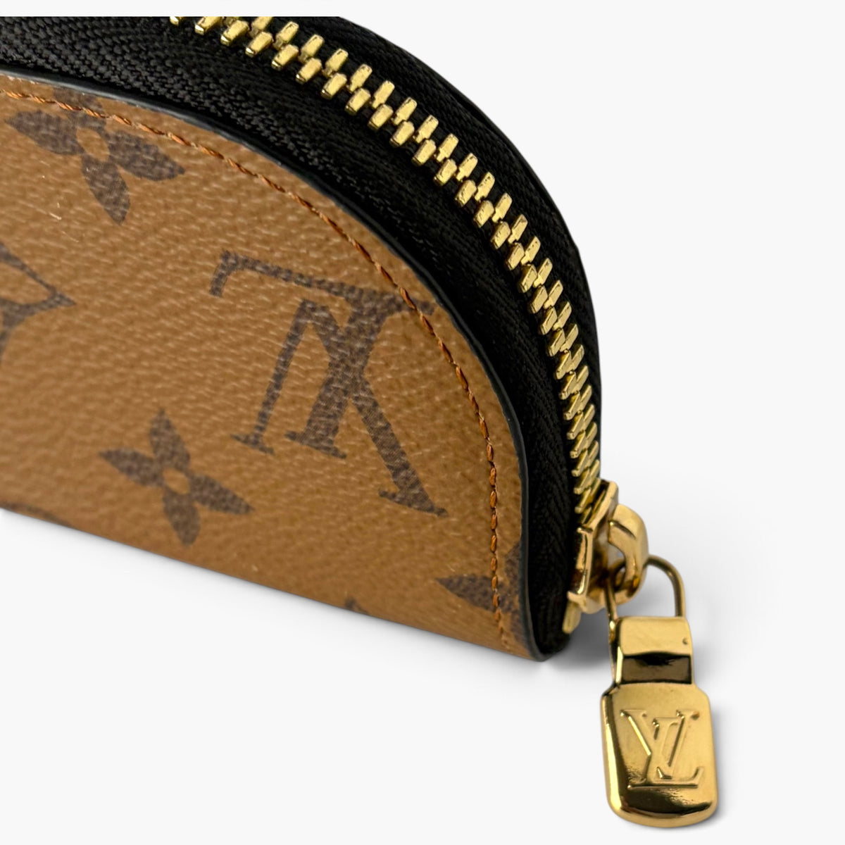 Brown monogram pencil case with black zipper and gold zipper pull, close-up