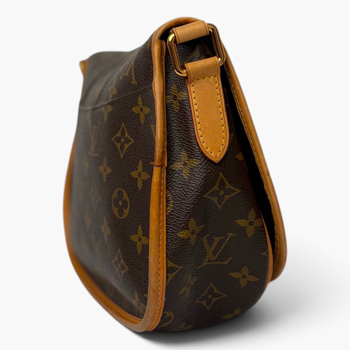 Monogram canvas shoulder bag side view with tan leather handle and stitched trim.
