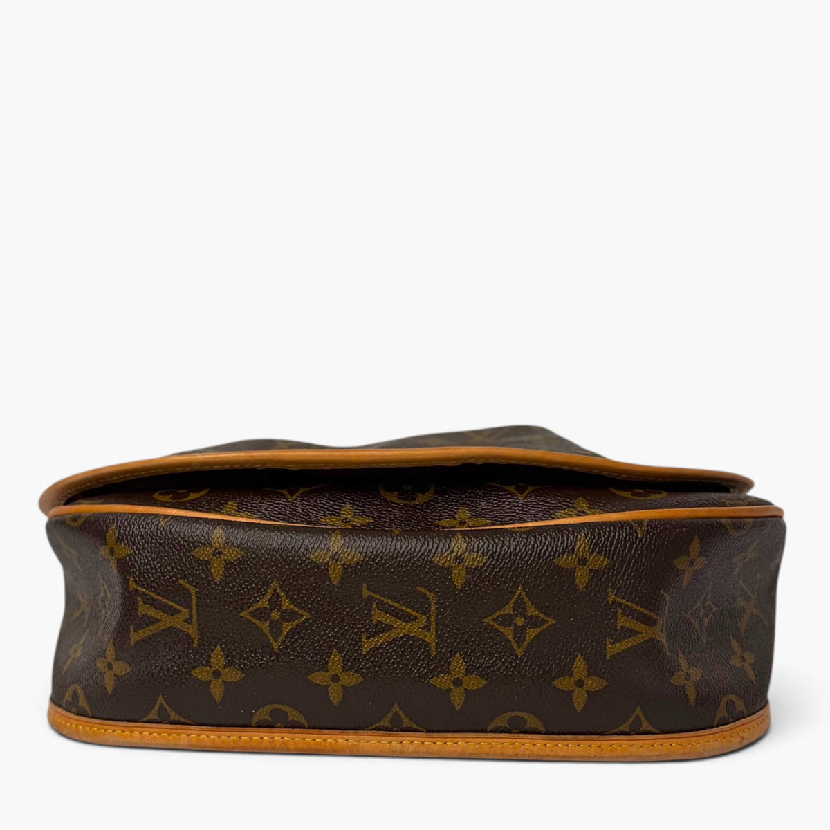 Monogram canvas bag with tan trim and stitched flap edge, side profile view.
