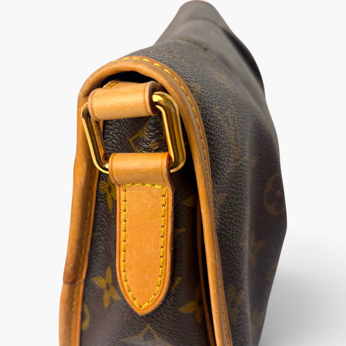 Close-up of adjustable strap hardware and tan leather D-ring on monogram bag.