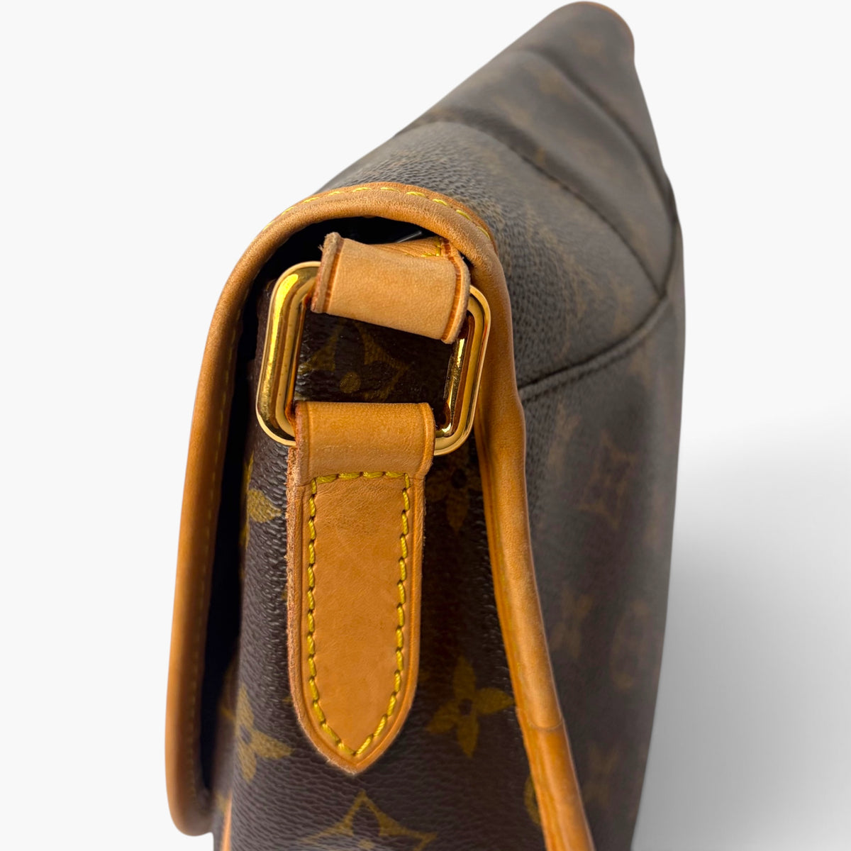 Monogram canvas bag with tan leather strap attachment and gold-tone buckle hardware.