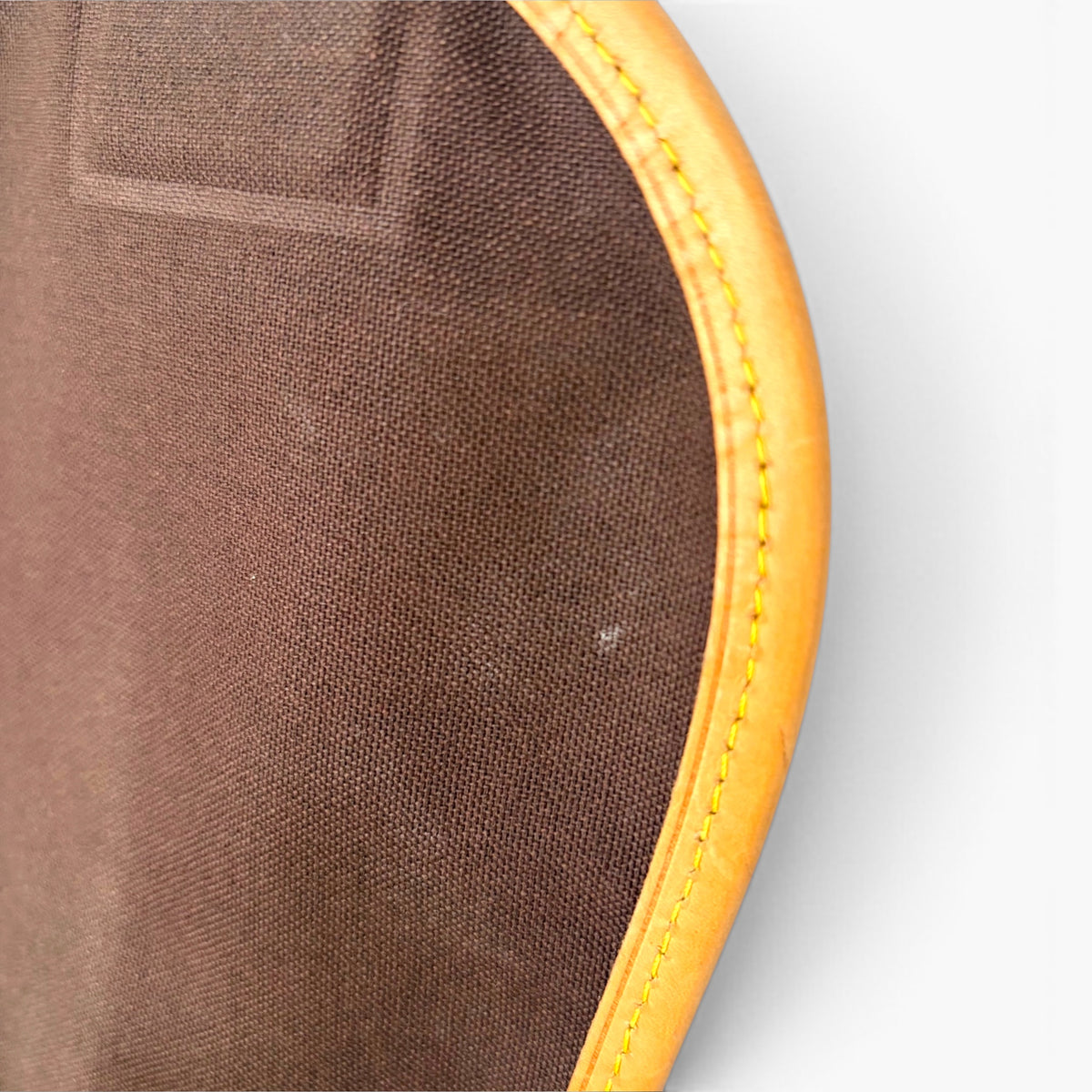 Brown fabric underside with tan stitched edge trim on the bag opening