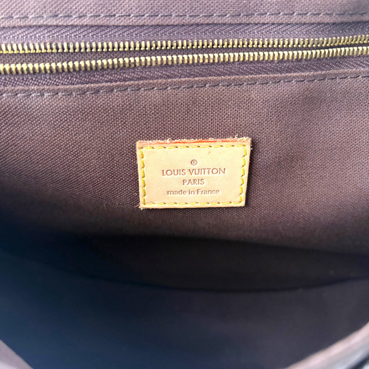 Brown fabric lining with sewn brand patch and zipper track visible inside