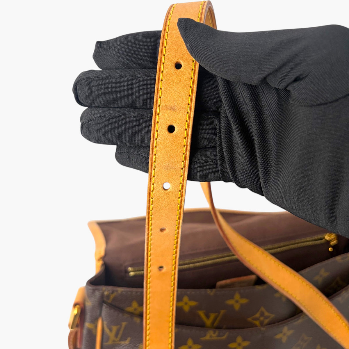 Shoulder strap attachment with rivets and black fabric cuff near the bag opening