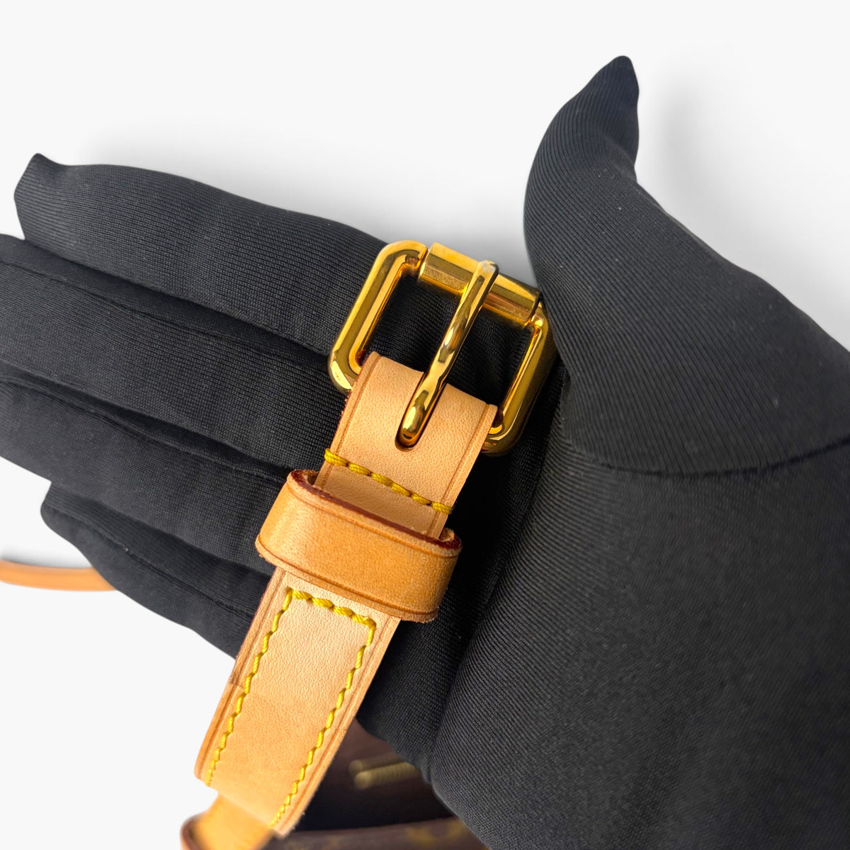 Gold-tone buckle and tan leather strap with stitched edging