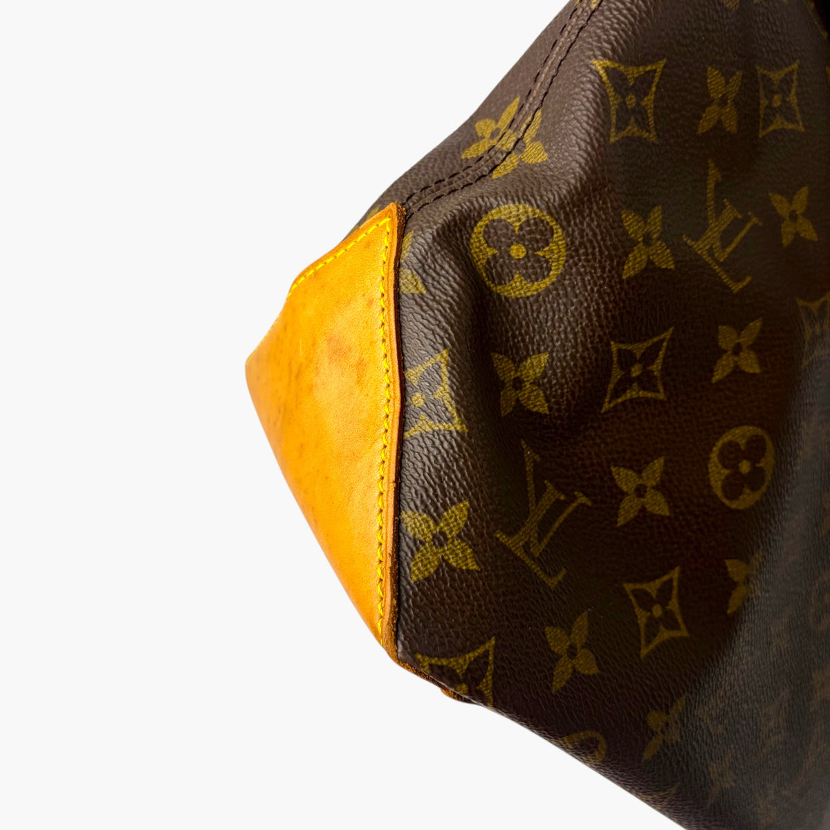Brown monogram canvas side panel with tan leather piping and bright yellow lining