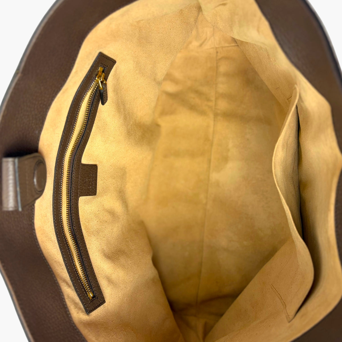 Tote bag interior with tan lining and zip pocket with gold-tone zipper hardware