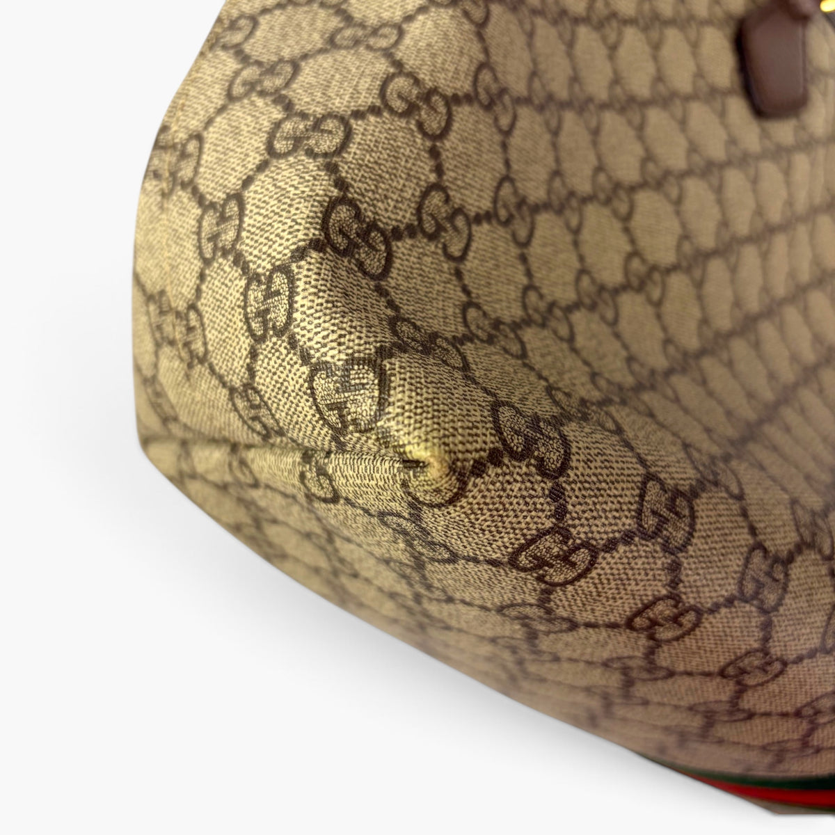 Beige GG Supreme canvas corner with embossed-style pattern and brown leather detail