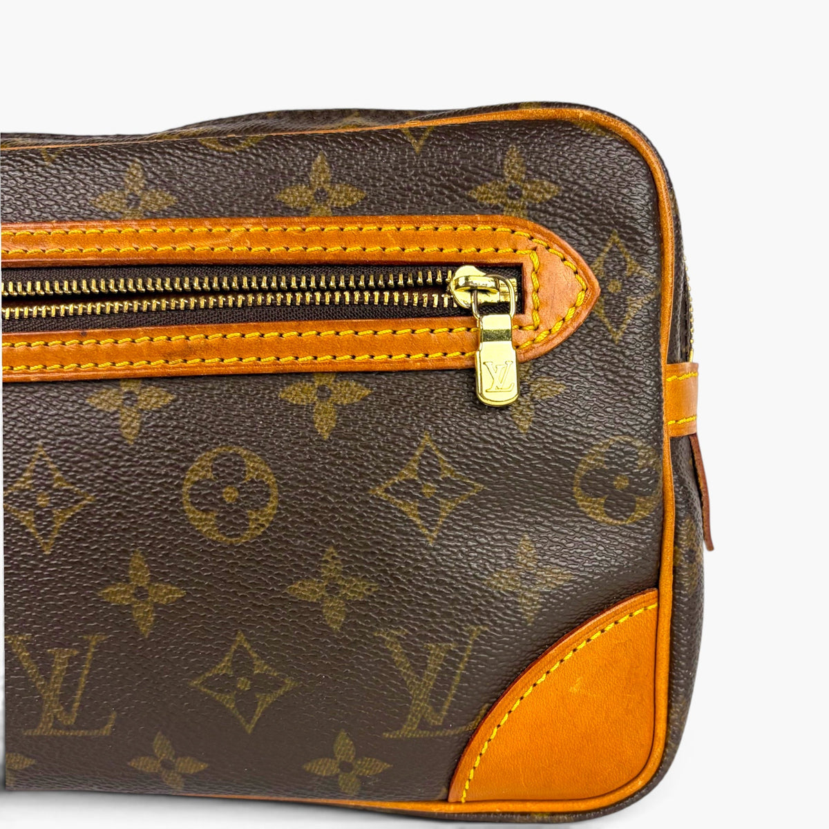 Monogram pouch front close-up: gold zipper pull and orange edge trim