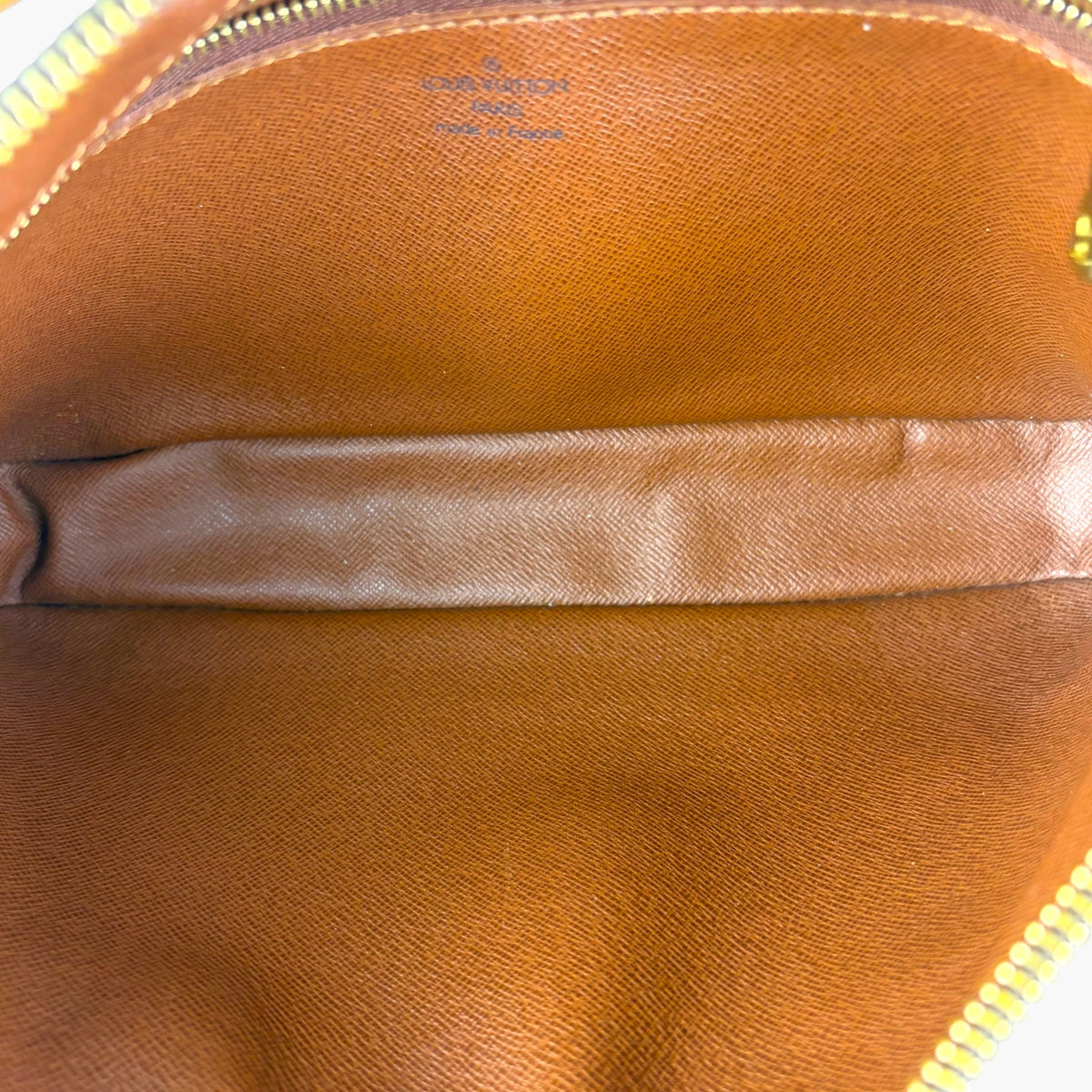 Tan leather interior of monogram pouch with stitched seam and zip edge