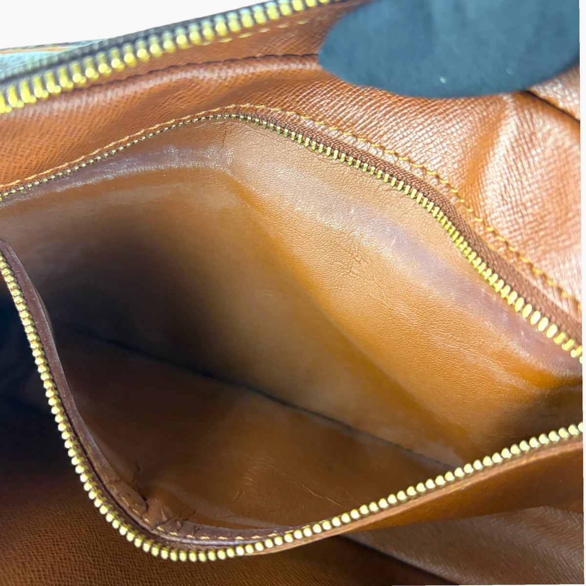 Monogram pouch interior pocket with tan lining and gold-tone zipper trim
