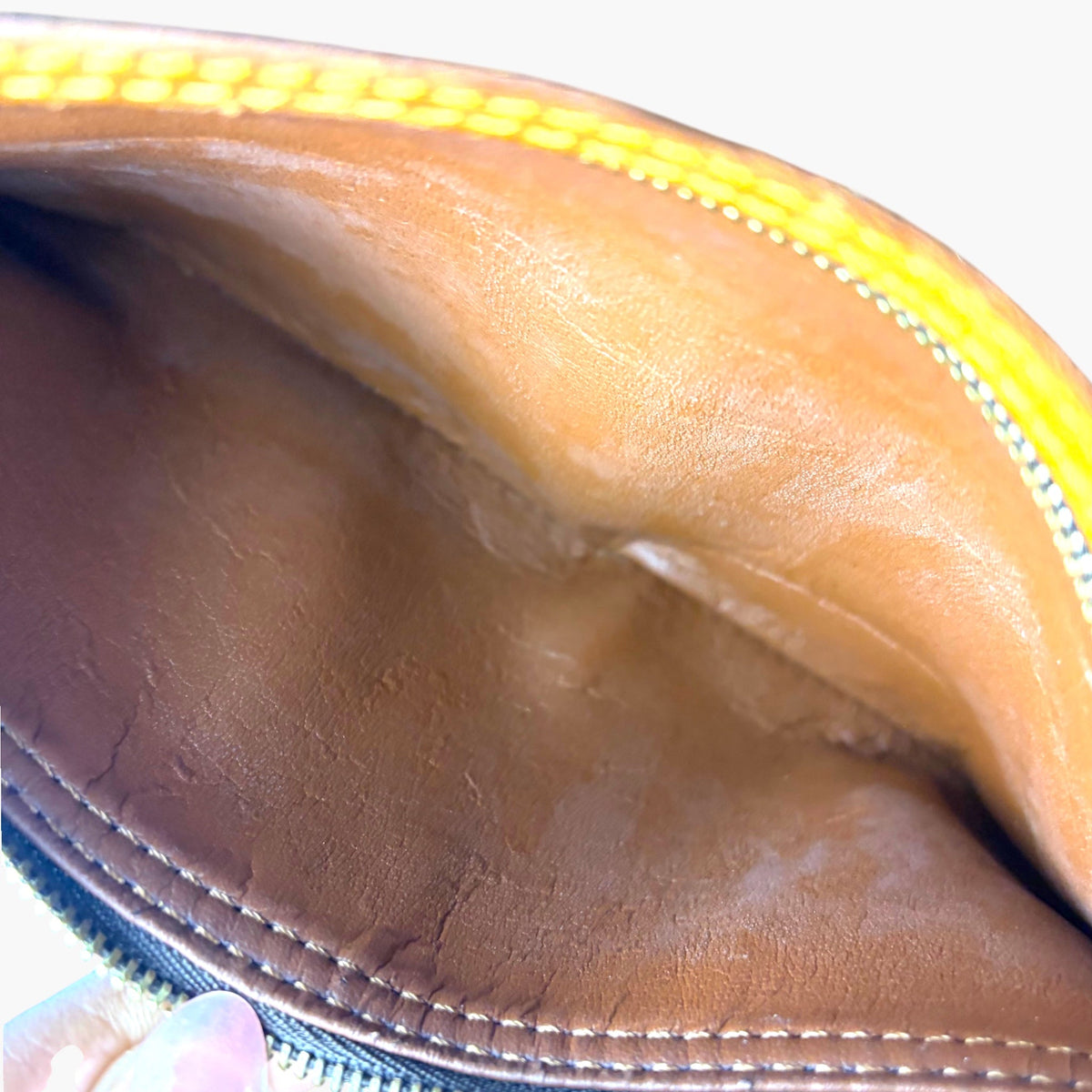 Tan leather lining inside monogram pouch with stitched seam and zipper edge