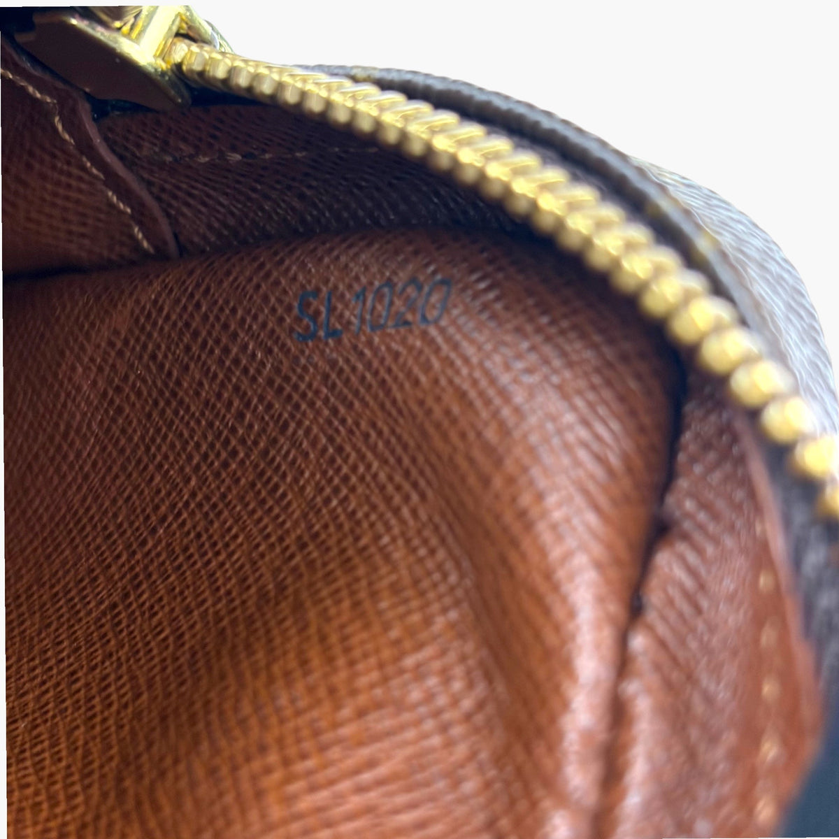 Monogram pouch interior with embossed date stamp and gold zipper edge
