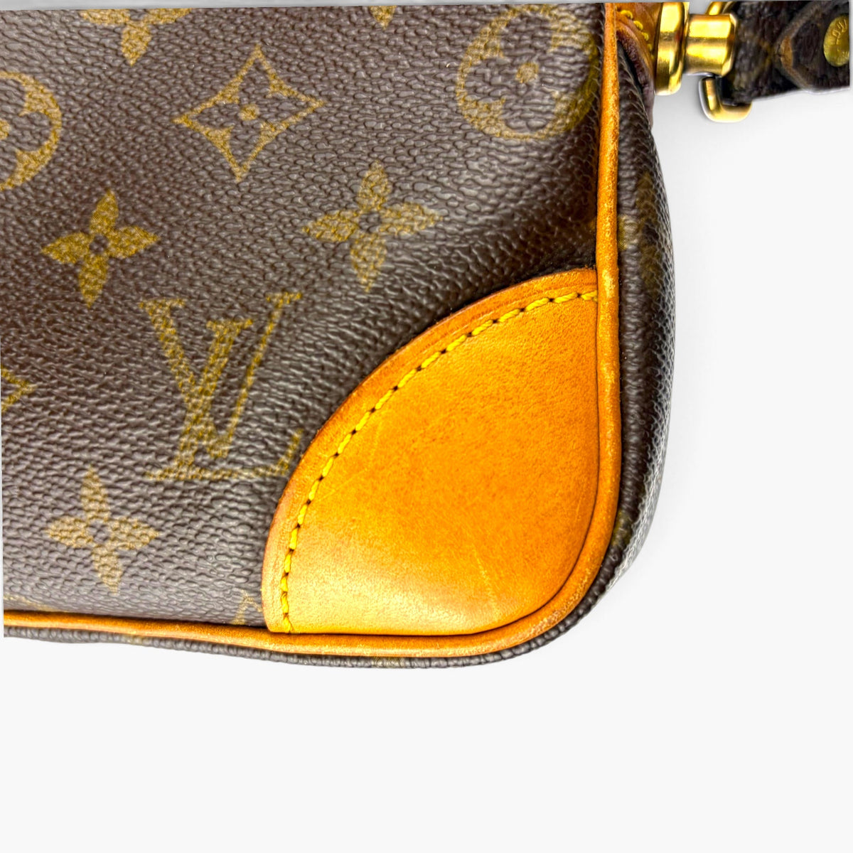 Monogram canvas pouch corner with tan leather trim and gold zipper hardware