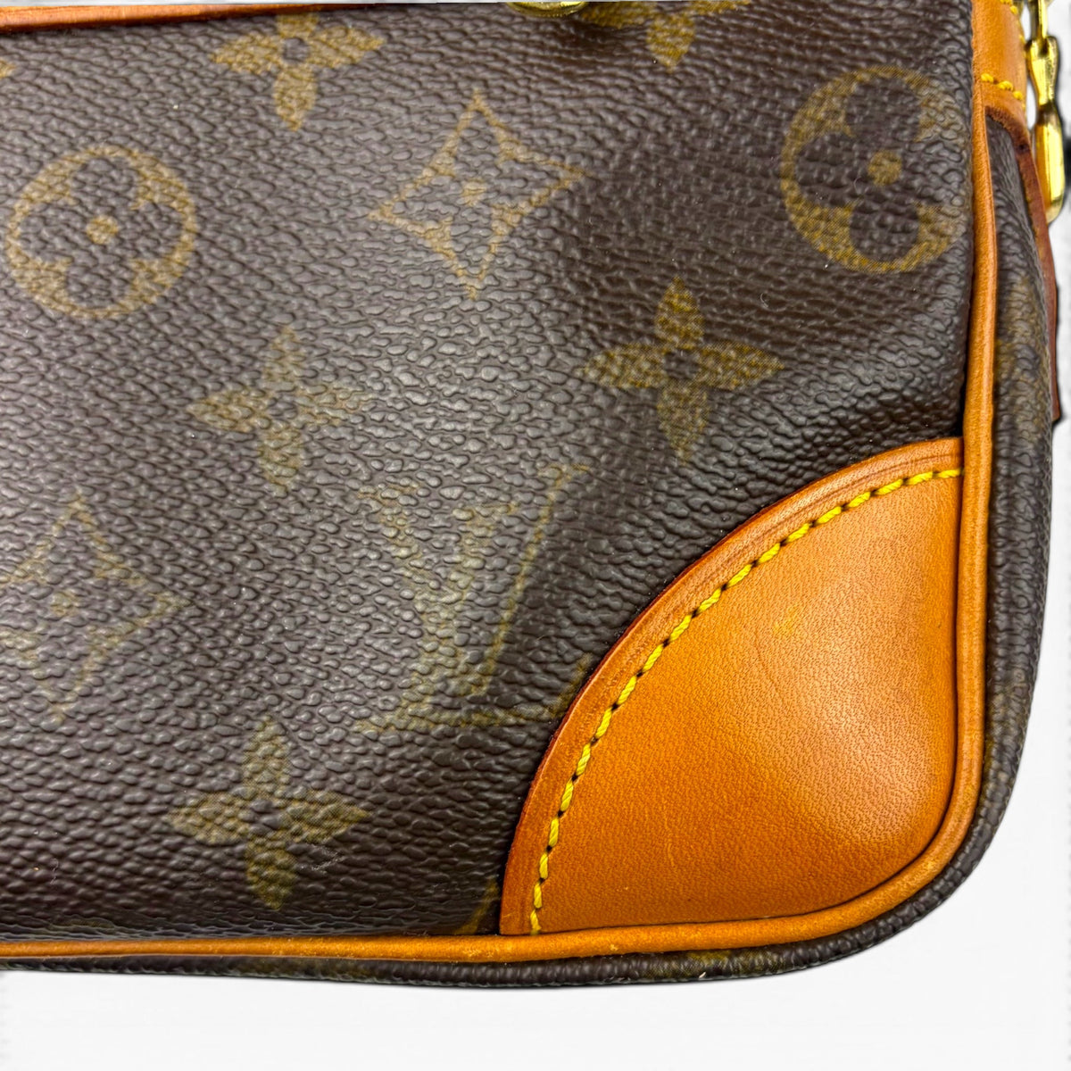 Monogram canvas pouch edge with tan leather trim and stitched curved panel