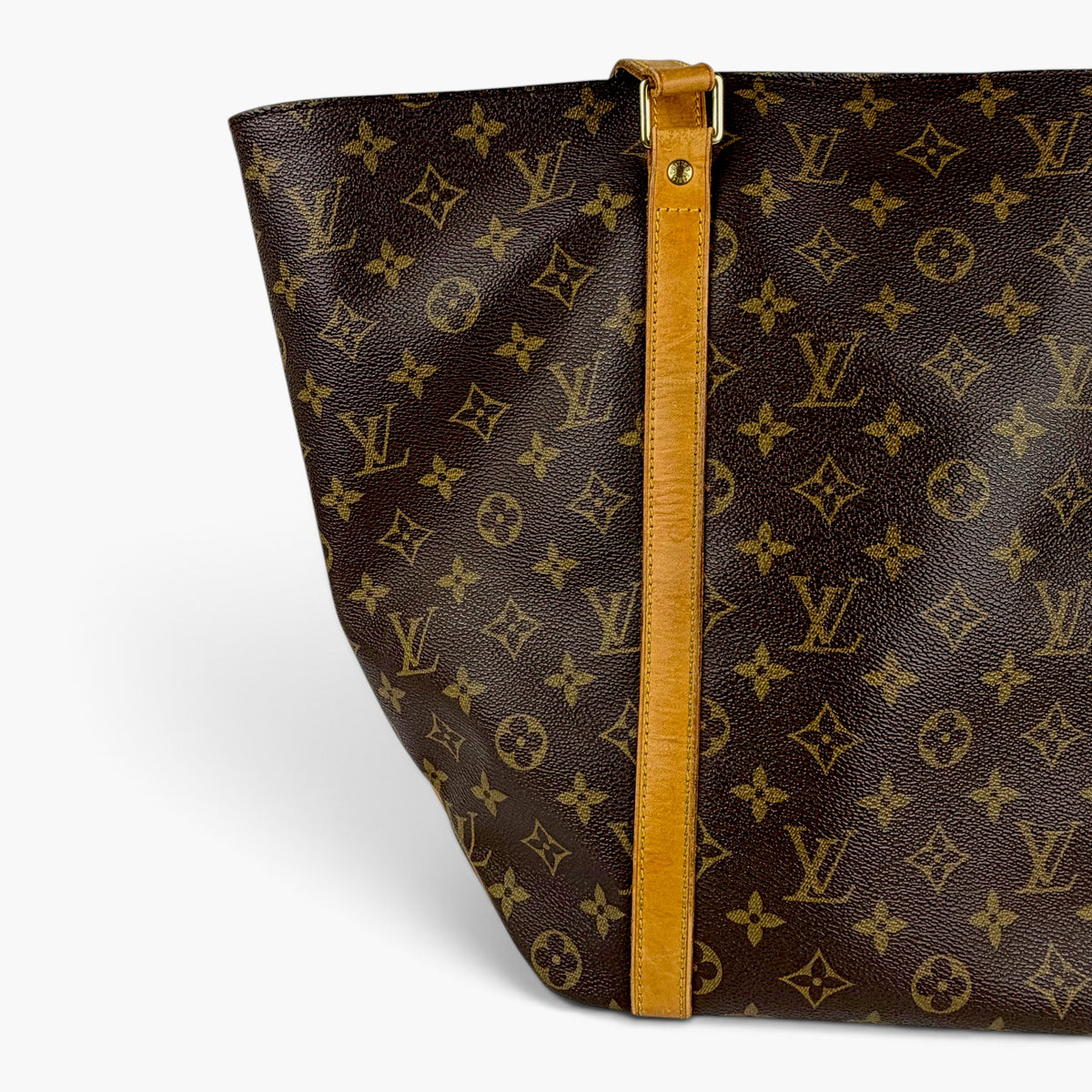 Monogram shopping tote bag corner with tan strap edge and gold-tone hardware