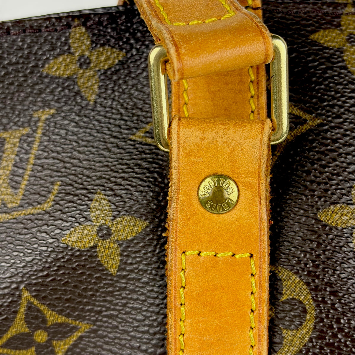 Tan leather strap close-up with metal buckle and round stamp detail