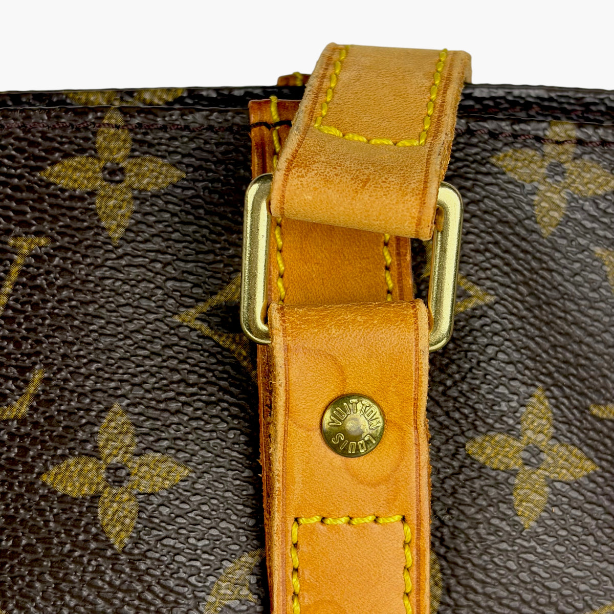 Close-up of tan strap hardware on brown monogram tote